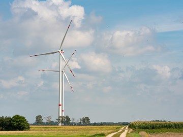 zwei Windraeder auf der Wiese Das Bild zeigt eine ländliche Landschaft mit zwei großen Windkraftanlagen, die in einem offenen Feld stehen. Ein unbefestigter Weg führt in Richtung der Windräder. Der Himmel ist teilweise bewölkt.