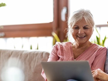 Mann und Frau sitzen auf dem Sofa und werfen auf dem Laptop einen Blick ins Kundenportal Mann und Frau sitzen auf dem Sofa und werfen auf dem Laptop einen Blick ins Kundenportal