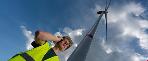 Mitarbeiter vor Windrad mit Handy Mitarbeiter vor Windrad mit Handy