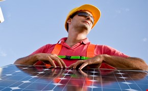 Windräder, Solarpanel und ein Mann in Arbeitskleidung symbolisieren Anpacken im Bereich erneuerbare Energien. Windräder, Solarpanel und ein Mann in Arbeitskleidung symbolisieren Anpacken im Bereich erneuerbare Energien.