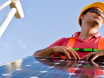 Windräder, Solarpanel und ein Mann in Arbeitskleidung symbolisieren Anpacken im Bereich erneuerbare Energien. Windräder, Solarpanel und ein Mann in Arbeitskleidung symbolisieren Anpacken im Bereich erneuerbare Energien.